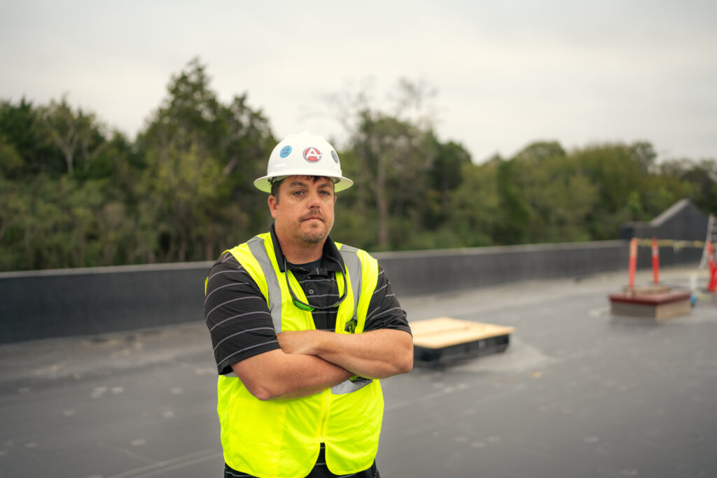 Austermiller roofer on commerical roof looking at camera.